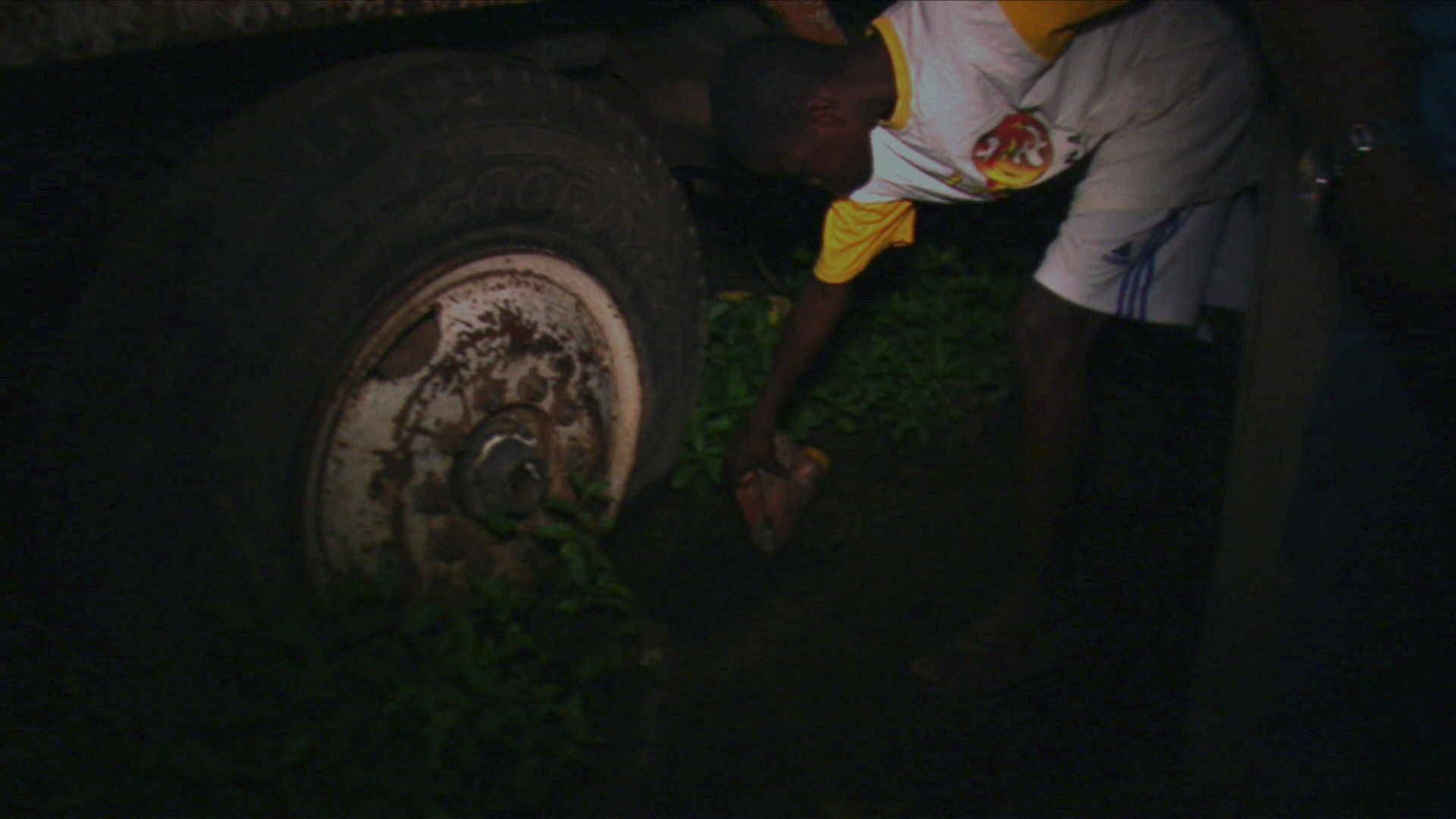 Michael, a school-aged boy, scoops water for cleaning and bathing from a pool formed around a decomposing truck tire in Accra. Image by Peter Sawyer. Ghana, 2011.