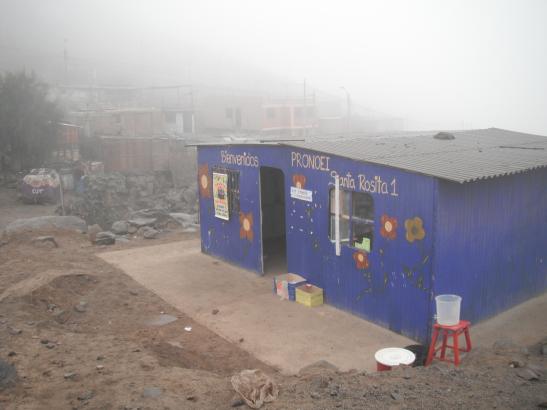 The Santa Rosita Kindergarten. The container on the right holds the water that is used by the 30 children and their teacher, Elisa Ribero Guia, for drinking, handwashing and flushing the toilet. Image by Simeon Tegel. Peru, 2012. Media file: Waterless Lima 048.jpg