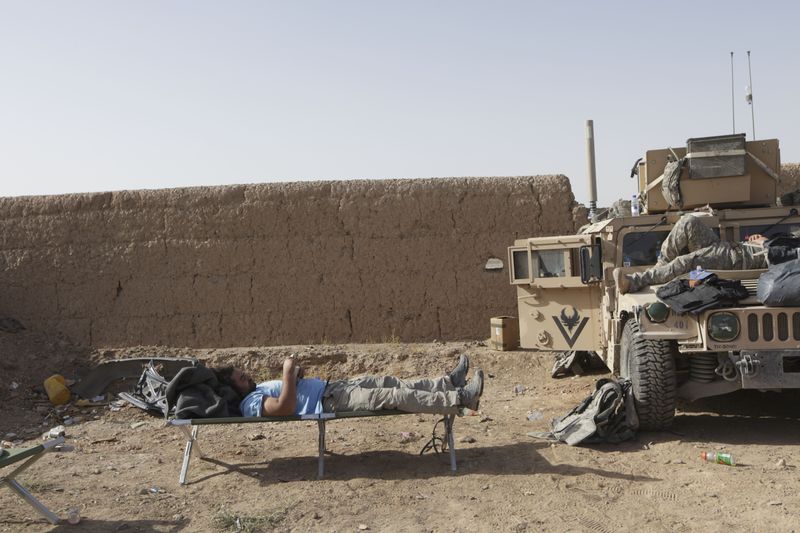 Nir Rosen resting at a checkpoint in Helmand manned by Afghan Police and American soldier.Image by Matthias Bruggermann. Afghanistan, 2009.