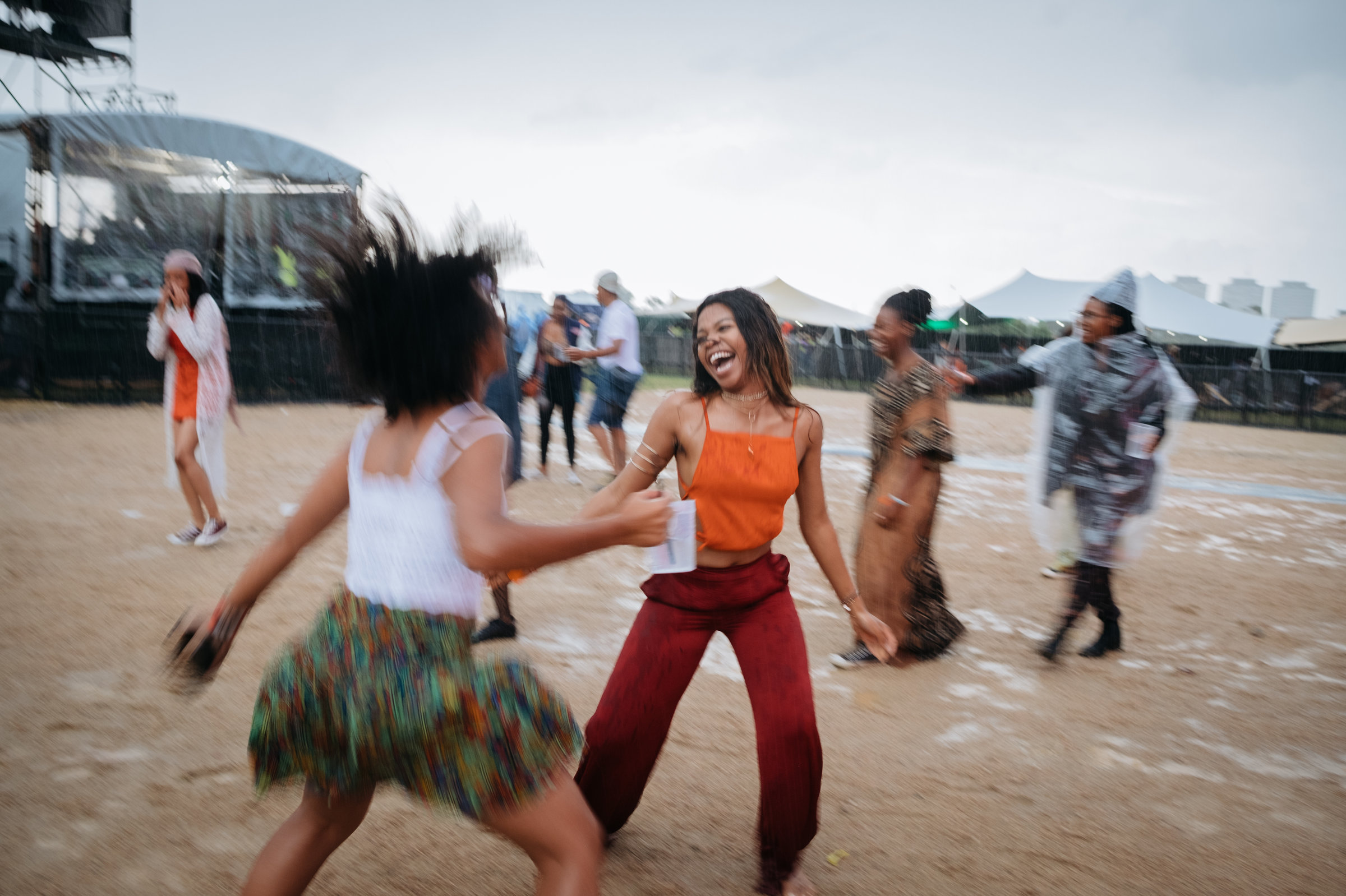 Rain can't dampen the spirits of Afropunk Joburg attendees. They continue to dance as rain begins to fall in Johannesburg in December. Image by Melissa Bunni Elian. South Africa, 2017. Rain can't dampen the spirits of Afropunk Joburg attendees. They continue to dance as rain begins to fall in Johannesburg in December. Image by Melissa Bunni Elian. South Africa, 2017.