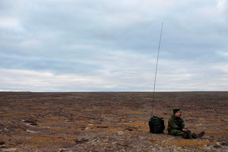 A soldier waits by his radio on the tundra near Blue Fox Harbor on Banks Island in the Canadian Arctic. The soldier was part of Operation Nanook, an annual “sovereignty operation,” in which Canadian forces patrol the nation’s northern territory. Image by Louie Palu. Canada, 2018. A soldier waits by his radio on the tundra near Blue Fox Harbor on Banks Island in the Canadian Arctic. The soldier was part of Operation Nanook, an annual “sovereignty operation,” in which Canadian forces patrol the nation’s northern territory. Image by Louie Palu. Canada, 2018.