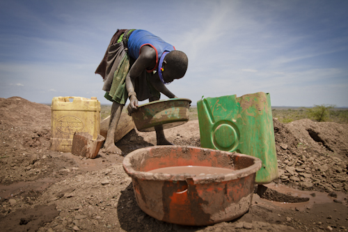 A Karamojong girl tries to extract gold from the earth that her partner has mined from one of the many pits scattered on the slopes of Mount Moroto at Rupa. Image by Marc Hofer. Uganda, 2011. image