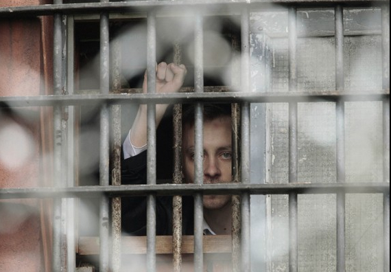 A Belarussian detainee, arrested during the flash mob in Minsk on July 7, gestures from a prison cell at a detention centre. Image by Vasily Fedosenko, Reuters. Minsk, Belarus, 2011. image