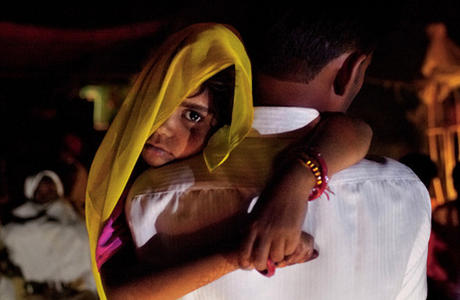 Long after midnight, 5-year-old Rajani is roused from sleep and carried by her uncle to her wedding. Child marriage is illegal in India, so ceremonies are often held in the wee hours of morning. It becomes a secret the whole village keeps, explained one farmer. Image by Stephanie Sinclair. India, 2011. image