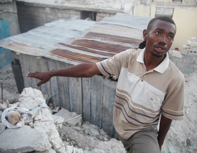 Damas Negrial gestures toward the skull discovered in the rubble near his Port-au-Prince home. Image by Andre Lambertson, Haiti, 2011.