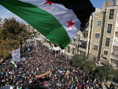 Syrian flag flies over a large gathering of protesters in Idlib. Image by Freedom House, Flickr. Syria, 2012. Media file: full_1334212784_e254df5cd7_z.jpg
