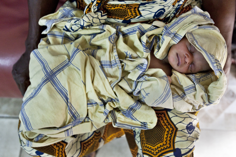 A newborn baby rests on its grandmother's lap. Image by Jake Naughton. Liberia, 2012. Media file: jnaughton-liberia-midwives.jpg