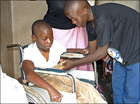 A family member helps Mariam in her wheelchair. Image by Sharon Schmickle. Uganda, 2008. Media file: kdfxm6.jpg