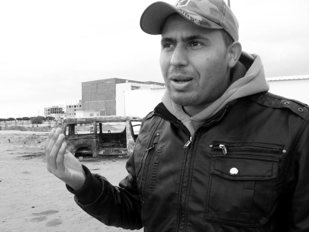 Hamza ben Abdallah, in front of the police station in Sidi Bouzid. Behind him is a police car that was burned during the protests. Image by Ellen Knickmeyer. Tunisia, 2011.