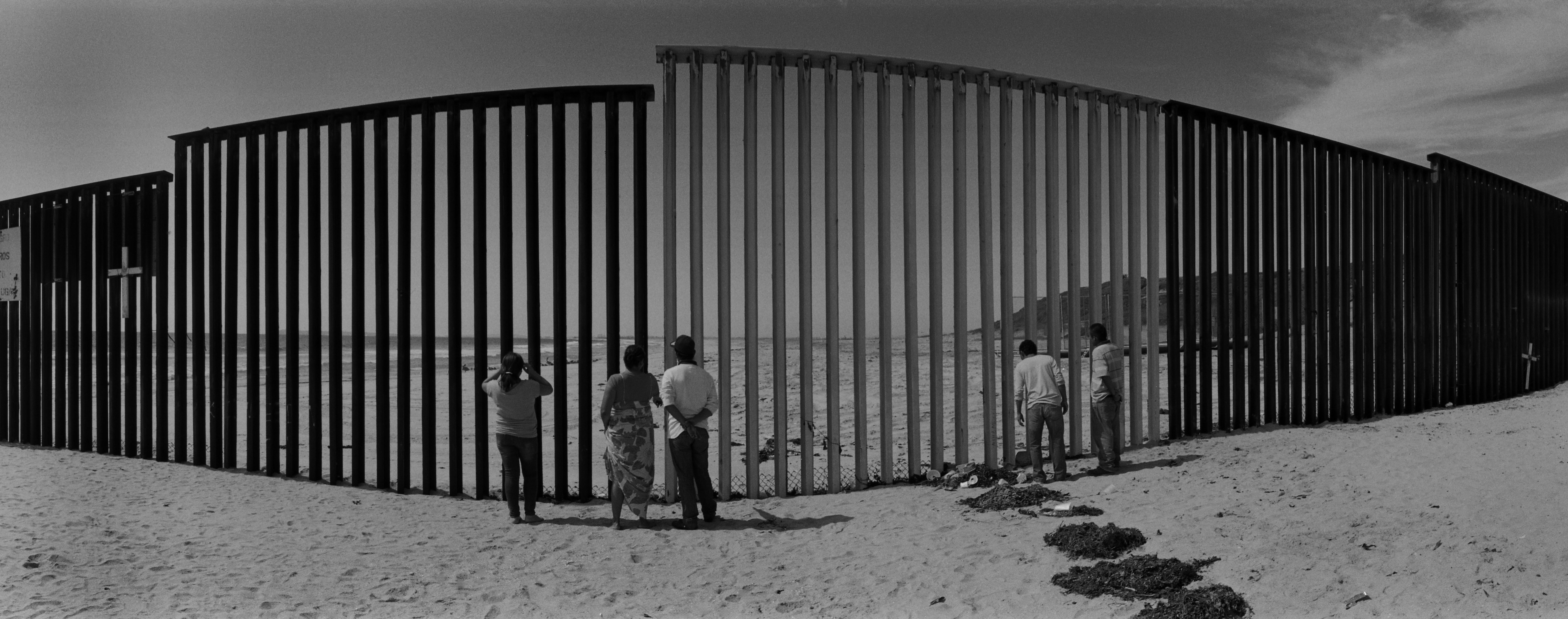 Mexicans look through the U.S.-Mexico border fence into the United States from a Mexican beach west of Tijuana. Image by © Louie Palu/ZUMA. Mexico, 2012. Media file: slideshow_tijuana_003.jpg