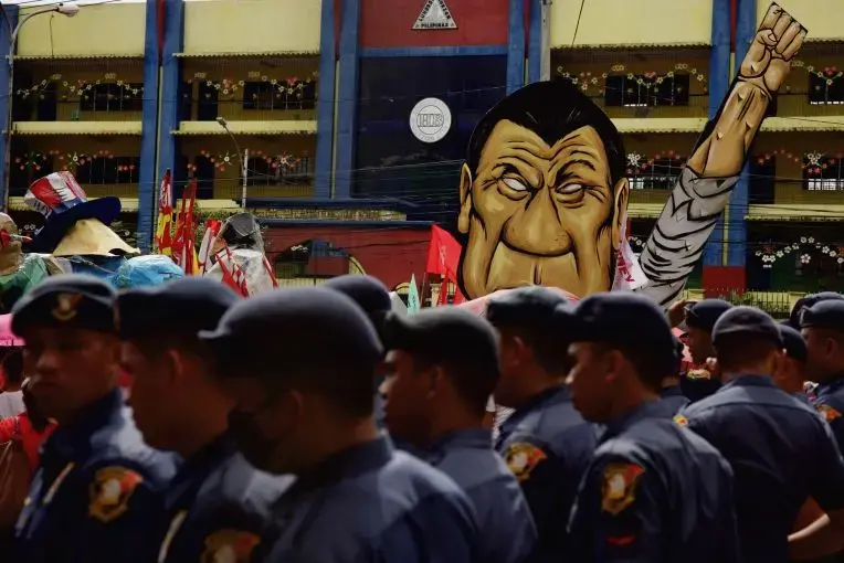 Law enforcement officers in front of an effigy of President Rodrigo Duterte during a rally against the extrajudicial killings and other issues in Quezon City, July 24, 2017. Image by Pat Nabong. Philippines, 2017. Law enforcement officers in front of an effigy of President Rodrigo Duterte during a rally against the extrajudicial killings and other issues in Quezon City, July 24, 2017. Image by Pat Nabong. Philippines, 2017.