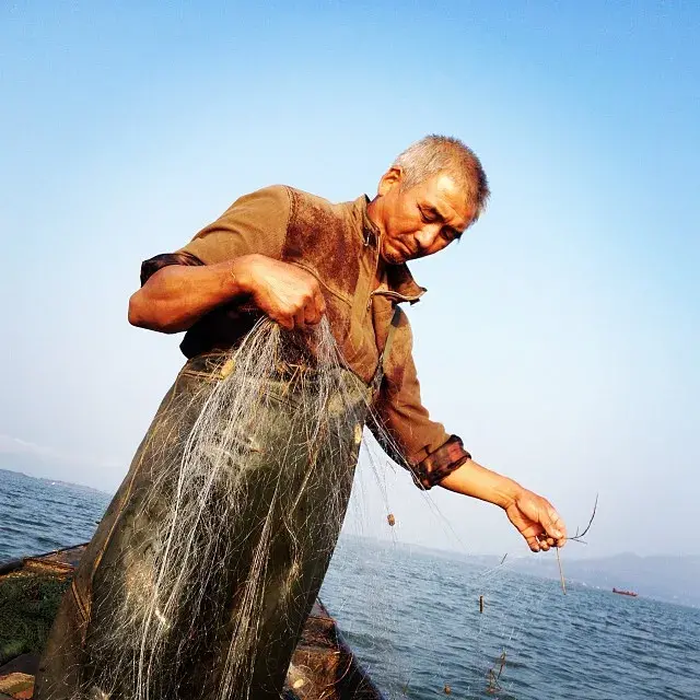Cao Suizhou, a Chinese fisherman on the Danjiangkou reservoir, is used to moving. He's been forcibly relocated three times for China's country’s colossal water projects and each time he's rebuilt his life from scratch. In 2009 Cao’s village was moved to make way for China's South-to-North Water Transfer Project, his small business was torn down along with his home. While Cao's wife relocated to the new village, Cao moved onto his boat to sustain the family’s livelihood. Image by Sharon Lovell. China, 2015. Media file: caosuizhou.jpg