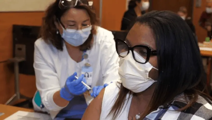 Tanara Gilbert, part of the Environmental Services team at UNC Rex Hospital receives the COVID vaccine during the initial rollout in December, 2020. Image courtesy of UNC Health. United States, 2020. Tanara Gilbert, part of the Environmental Services team at UNC Rex Hospital receives the COVID vaccine during the initial rollout in December, 2020. Image courtesy of UNC Health. United States, 2020.