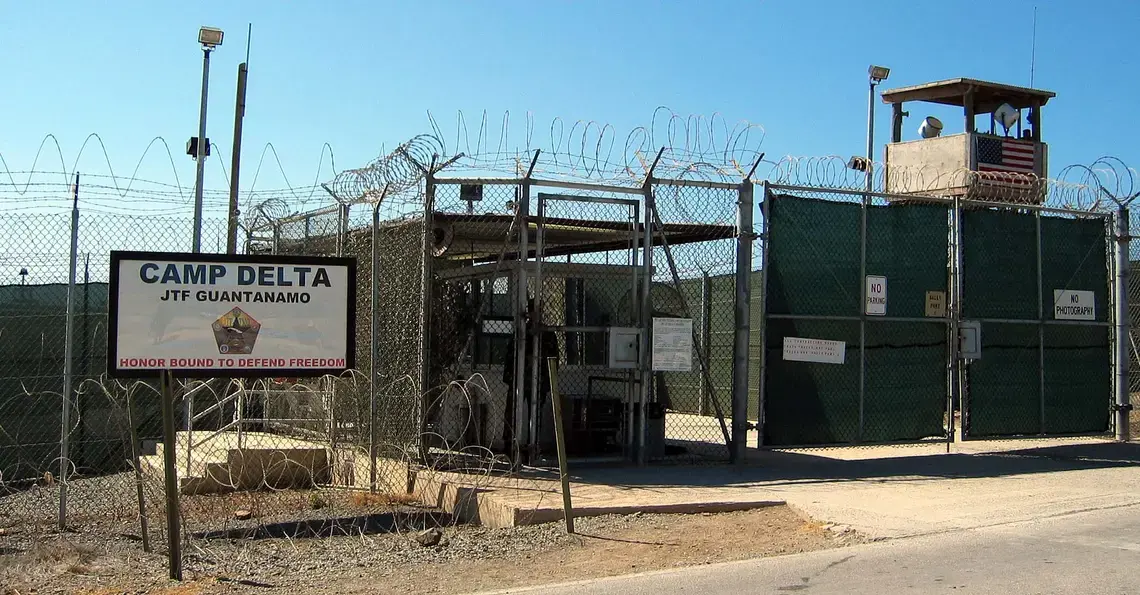 The entrance to Camp 1 in Guantanamo Bay's Camp Delta. The base's detention camps are numbered based on the order in which they were built, not their order of precedence or level of security. Photo by Kathleen T. Rhem. Cuba, 2018. Source: Wikimedia Commons. The entrance to Camp 1 in Guantanamo Bay's Camp Delta. The base's detention camps are numbered based on the order in which they were built, not their order of precedence or level of security. Photo by Kathleen T. Rhem. Cuba, 2018. Source: Wikimedia Commons.
