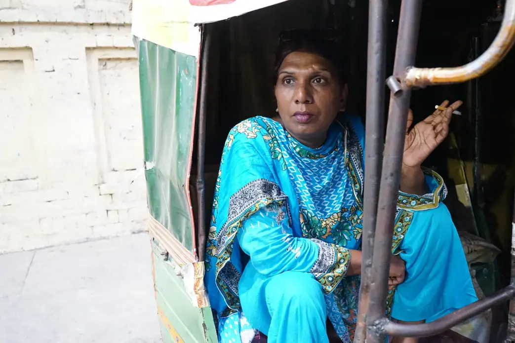 Ashi Jaan, age 45, takes a break from the protest to sit and smoke a cigarette while chatting with the rickshaw driver. Image by Ikra Javed. Pakistan, 2016. Ashi Jaan, age 45, takes a break from the protest to sit and smoke a cigarette while chatting with the rickshaw driver. Image by Ikra Javed. Pakistan, 2016.