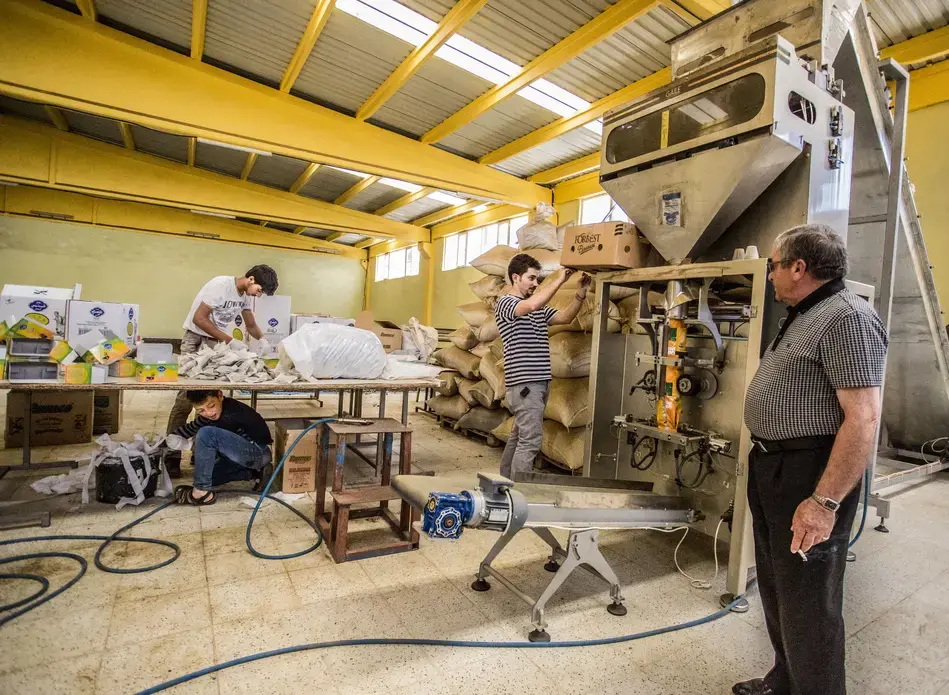 A young Syrian refugee packs tea boxes under a table in a Turkish factory near his refugee camp on the Turkey-Syria border. Image by Emily Kassie. Turkey, 2016. A young Syrian refugee packs tea boxes under a table in a Turkish factory near his refugee camp on the Turkey-Syria border.