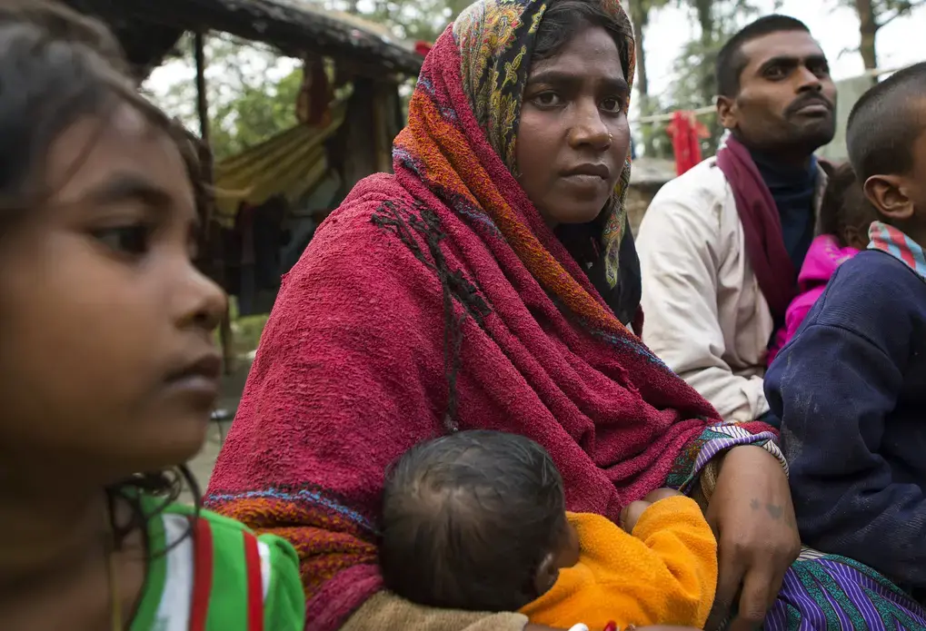 Sonia Devi, 35, holds her 2-month-old daughter Lovely, as she sits with her family at her home in a village in Begusarai, Bihar, one afternoon in December. Sonia was sterilized a few days earlier. She has three other children besides Lovely—Suraj, 10, Laxmi, 6, and Badal, 2—and decided she didn't want to have a fifth. Image by Sarah Weiser. India, 2014. Media file: sw_sonia_pcphoto.jpg