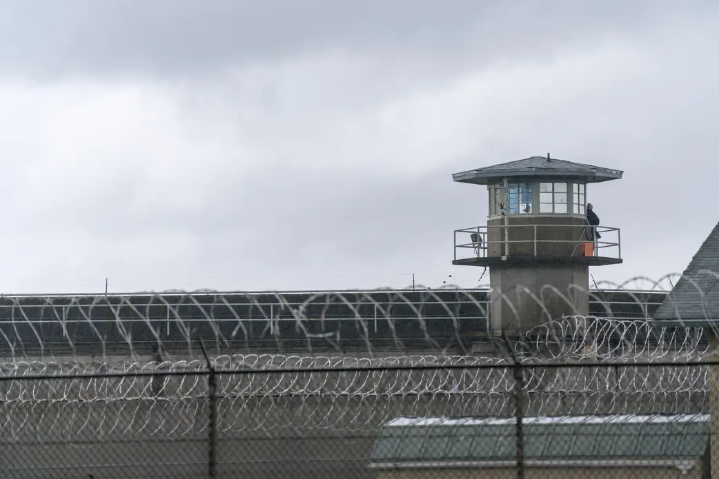 An armed guard surveys the grounds from the railing of a prison watchtower. Image by RealWindowCreative/shutterstock. Undated. An armed guard surveys the grounds from the railing of a prison watchtower. Image by RealWindowCreative/shutterstock. Undated.
