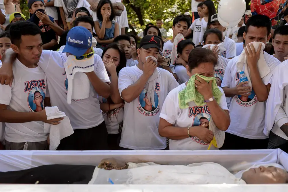 Family and friends of Alvin John Mendoza mourn as they spend their last moments with him on the day of his funeral on October 23, 2016. Mendoza, 23, was killed by unidentified riding-in-tandem gunmen while he was eating in a canteen near his home. Image by Eloisa Lopez. Philippines, 2016. A family and friends of the deceased grieve standing before an open casket.