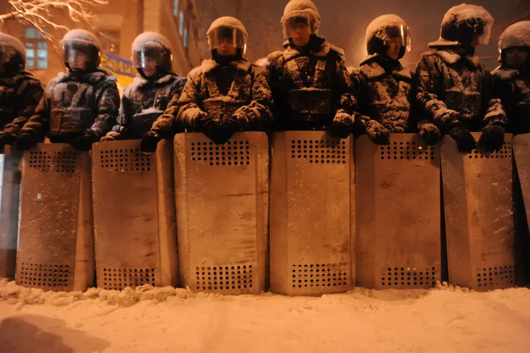 A line of riot police officers under the heavy snow fall in Kiev. Image by Mstyslav Chernov/Unframe. Courtesy of Wikicommons. Ukraine, 2013. Media file: a_line_of_riot_police_officers_under_thr_heavy_snow_fall_in_kiev_as_the_city_prepares_for_the_predictably_violent_attack_from_the_police._december_9_2013.jpg