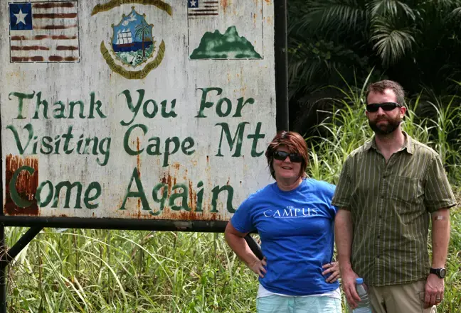 Photojournalist Cheryl Hatch and writer Brian Castner pose for a photograph as they leave Grand Cape Mount county in Liberia on Thursday, Jan. 15, 2015. Hatch is also the adviser to the student newspaper, The Campus, at Allegheny College, and she promised the students she'd take a photo with the shirt somewhere on her trip. Image by Prince Collins. Liberia, 2015. Media file: grandcapemount_9247.jpg