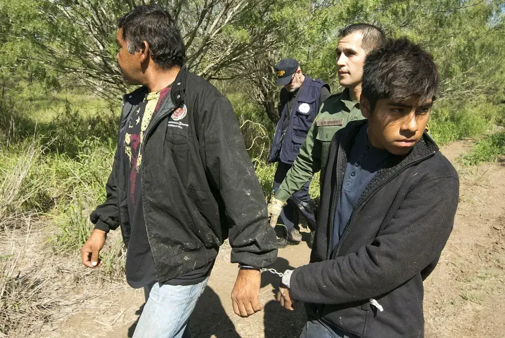 Border Patrol Agent Roberto Rodriguez escorts two Mexican nationals apprehended near the Texas-Mexico border on Oct. 12, 2017. Image by Marjorie Kamyd. United States, 2017. Border Patrol Agent Roberto Rodriguez escorts two Mexican nationals apprehended near the Texas-Mexico border on Oct. 12, 2017. Image by Marjorie Kamyd. United States, 2017.