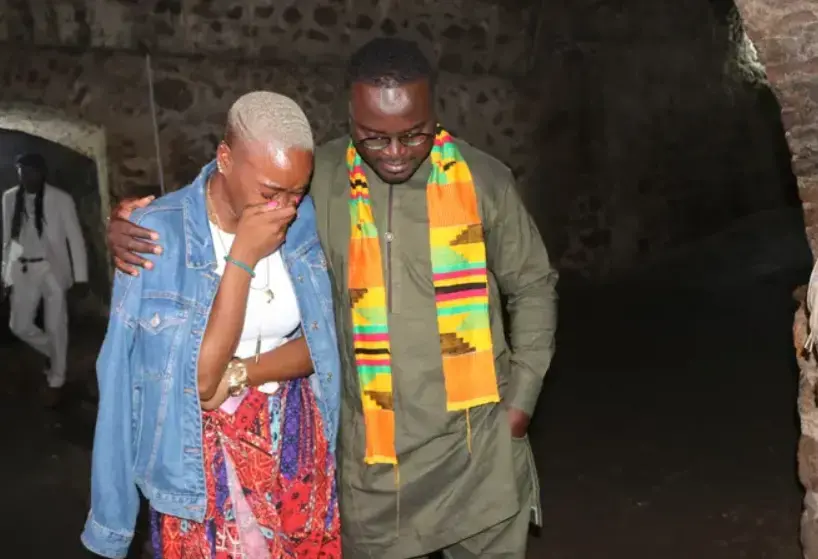 A tour guide comforts NAACP Youth and College Director Dena Loftin inside the Cape Coast Slave Castle on Ghana's coast. Africans captured by slave traders were herded inside small dungeons and endured horrendous conditions before being put on a ship to lands unknown. Those who died were thrown to the sharks; those who survived were sent across the sea in chains. Image by NAACP. Ghana, 2020. A tour guide comforts NAACP Youth and College Director Dena Loftin inside the Cape Coast Slave Castle on Ghana's coast. Africans captured by slave traders were herded inside small dungeons and endured horrendous conditions before being put on a ship to lands unknown. Those who died were thrown to the sharks; those who survived were sent across the sea in chains. Image by NAACP. Ghana, 2020.