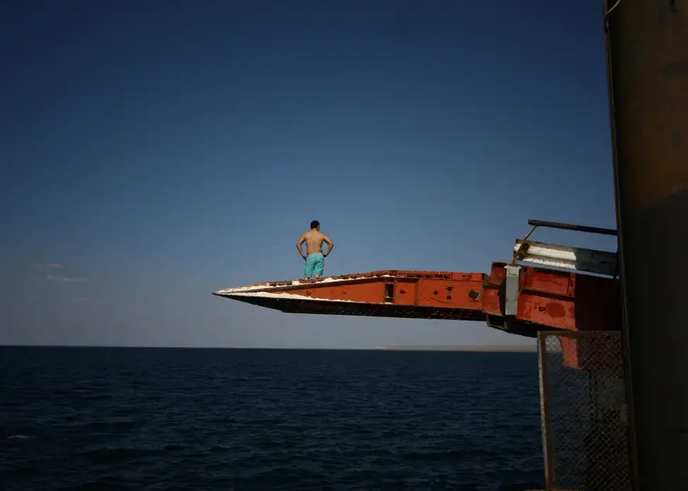 A man prepares to dive off a pier into the Caspian Sea in Sarytas, Kazakhstan, next to the spot where Russian geographers have determined is the true Europe–Asia border. Image by Joshua Kucera. Kazakhstan, 2016. A man prepares to dive off a pier into the Caspian Sea in Sarytas, Kazakhstan, next to the spot where Russian geographers have determined is the true Europe–Asia border. Image by Joshua Kucera. Kazakhstan, 2016.