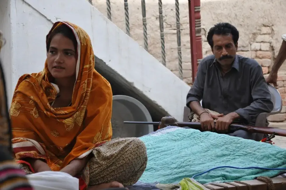 After Pakistani teen Kainat Soomro reported her four alleged rapists to police, tribal elders ordered her death in an "honor killing." Armed guards now accompany her every time she leaves her house. Image courtesy of H2H Films/Frontline. Pakistan. Media file: pakistan_armedguard.jpg