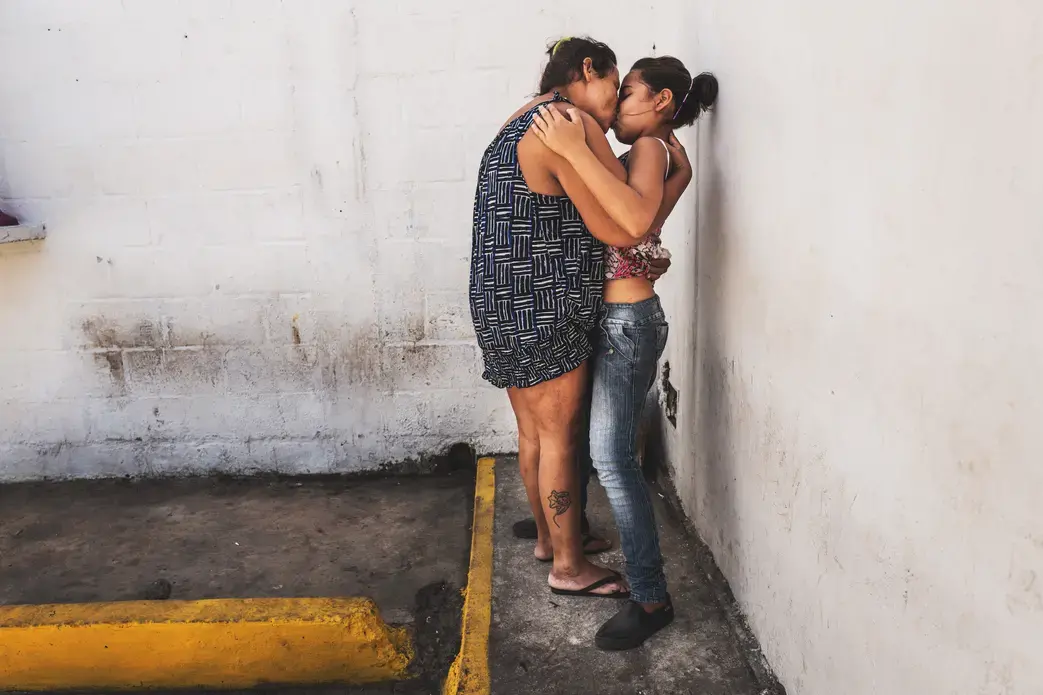 POLI-VALENCIA, CARABOBO - March 2018. Maria (on the left) kisses her daughter on visitation hours. She is 35 years old and is charged with robbery. She goes to therapy three times a week. While the beginning of the trials keep on being delayed, the condition of these women inside this precinct in the center of Valencia, a city on north-center of the country, has improved slightly between 2017 and 2018. They are now permitted to have a cellphone, hairdressing utensils and a 3hour recreation time outside their cell. Conjugal visitations are not allowed to female detainees, although one of them got pregnant while being inside the center with another male detainee; they had intercourse in the reception offifice. Image by Ana María Arévalo. Venezuela, 2018. POLI-VALENCIA, CARABOBO - March 2018. Maria (on the left) kisses her daughter on visitation hours. She is 35 years old and is charged with robbery. She goes to therapy three times a week. While the beginning of the trials keep on being delayed, the condition of these women inside this precinct in the center of Valencia, a city on north-center of the country, has improved slightly between 2017 and 2018. They are now permitted to have a cellphone, hairdressing utensils and a 3hour recreation time outside…