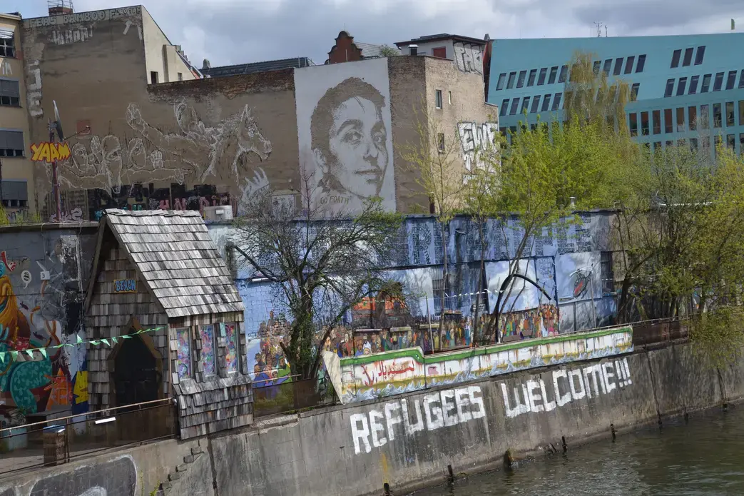 A mural in Berlin says "Refugees Welcome." Image by Jeanne Menjoulet. Berlin, 2016. A mural in Berlin says "Refugees Welcome." Image by Jeanne Menjoulet. Berlin, 2016.