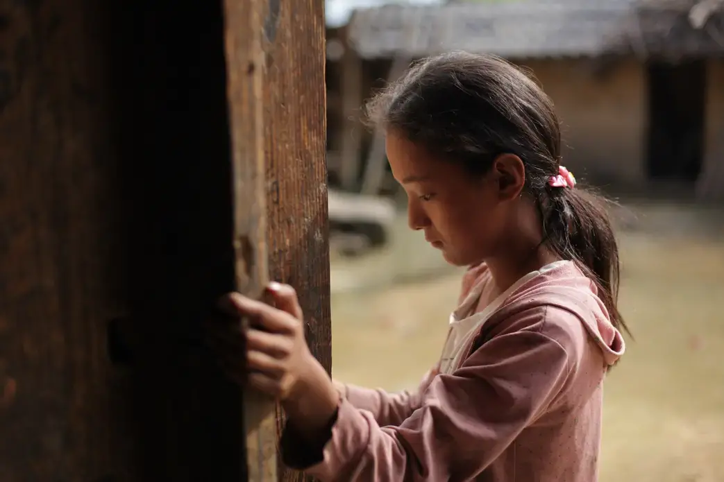 Down from the Mountains Media file: twelve-year-old_wang_bing_stands_by_the_door_of_her_familys_farmhouse_in_liangshan_prefecture_sichuan_province_china_july_2016.jpg