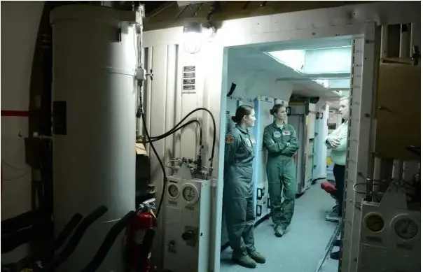 Right to left, PBS NewsHour special correspondent Jamie McIntyre with 1st Lt. Kathleen Fosterling and Deputy Missile Crew Commander 2nd Lt. Christina Camp, inside the underground nuclear launch-control center. Image by Dan Sagalyn. United States, 2016 Media file: bunker_photo-mcintyre.jpg