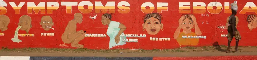 On SKD Boulevard in Monrovia, a man walks by a mural that illustrates the symptoms of Ebola. Image by Cheryl Hatch. Liberia, 2014. Media file: ebolasymptoms_4972-3.jpg