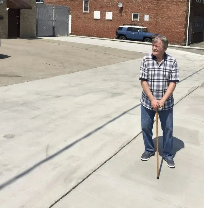Elliot Feltner stands on the sidewalk in front of the auto body shop that was in his family for decades. Image courtesy of Eye on Ohio. United States, 2020.