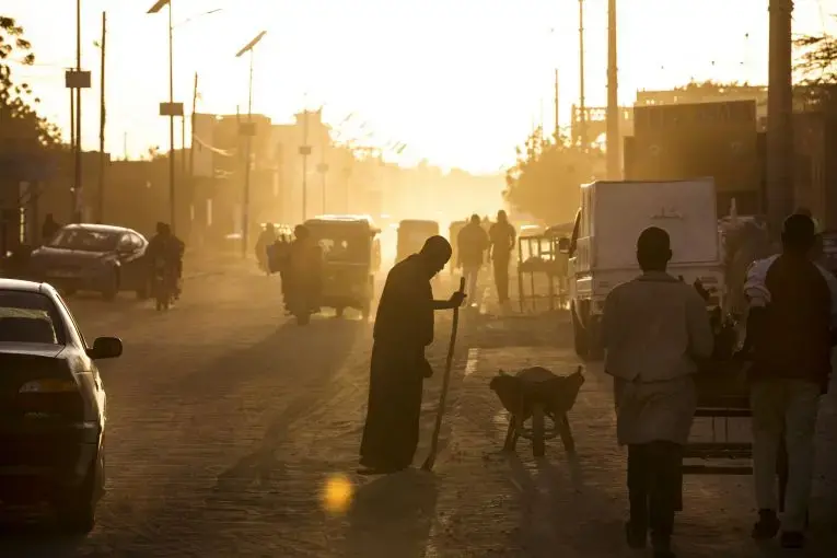 A man sweeps dust off the street at dusk in Agadez, Niger, January 16, 2018. Image by Joe Penney. Niger, 2018.