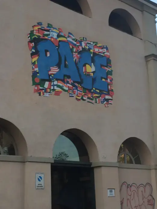 Graffiti on a building near the Olympic Village: "Pace," which translates to "Peace." Image by Akela Lacy. Italy, 2014. Media file: img_3652.jpg