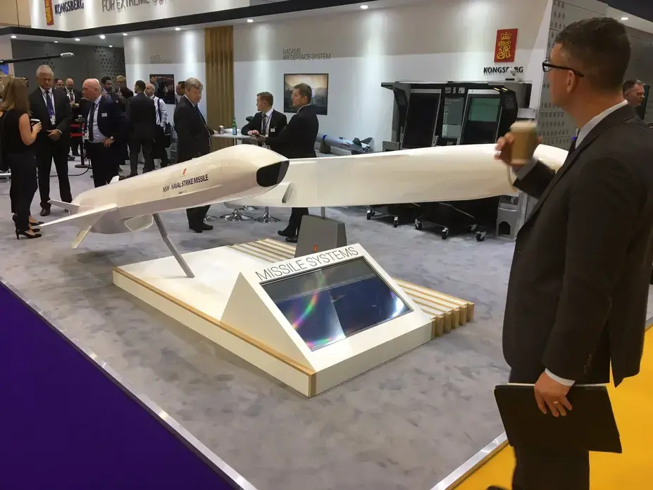 A man drinks a coffee and checks out a missile system for sale at London's DSEI arms fair, the biggest in the world. Image by Matt Kennard. England, 2017. Media file: djhogmwxcaeu6wi.jpg