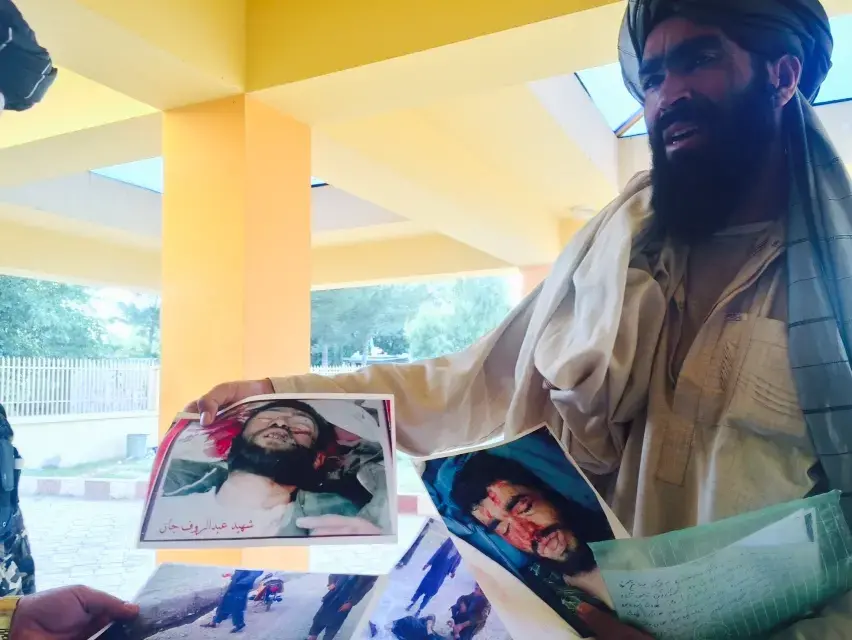 A family member of victims of Abdul Hakim Shujayi, a US-funded militia commander in Uruzgan. Image by May Jeong. Afghanistan, 2015. A man holds photographs of his and others' family members, victims of Abdul Hakim Shujayi, a US-funded militia commander in Uruzgan, Afghanistan.