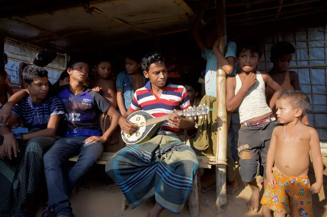 Musician holding a mandolin, surrounded by listeners. Image by Faiham Ebna Sharif. Bangladesh, 2019.