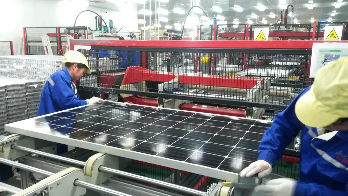 Workers assemble a solar panel at Jinko Solar’s factory in Haining, Zhejiang province. China is in the midst of the world’s biggest-ever investment in renewable power, seeking to reduce its reliance on coal and ease air pollution that is estimated to kill more than a million people in the country every year. Image by Beth Gardiner. China, 2017. Workers assemble a solar panel inside of a factory in Haining, Zhejiang province, China.