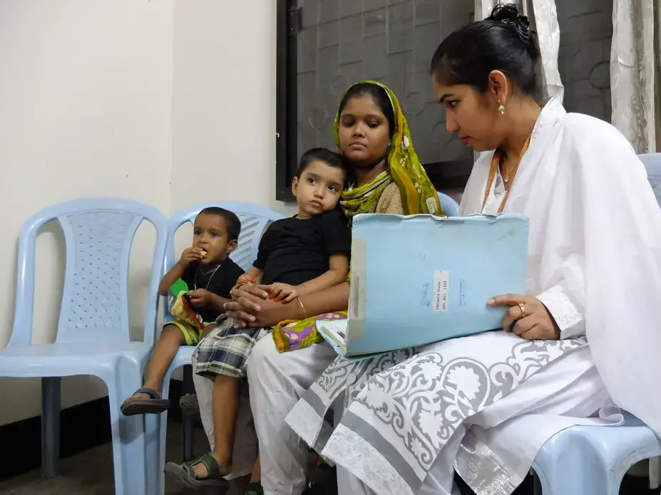 Mohommad Mustakim and his mother talk with researchers as part of a study of the rotavirus vaccine in Dhaka, Bangladesh. Mohommad got sick with rotavirus diarrhea even after getting the vaccine. Image by Carina Storr. Bangladesh, 2016. Media file: mustakim.jpg