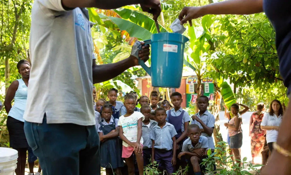 School children near Mirebalais are shown how to mix oral rehydration solution as part of an effort to head off any recurrence of cholera in Haiti. Image by Allison Shelley. Haiti, 2020. School children near Mirebalais are shown how to mix oral rehydration solution as part of an effort to head off any recurrence of cholera in Haiti. Image by Allison Shelley. Haiti, 2020.