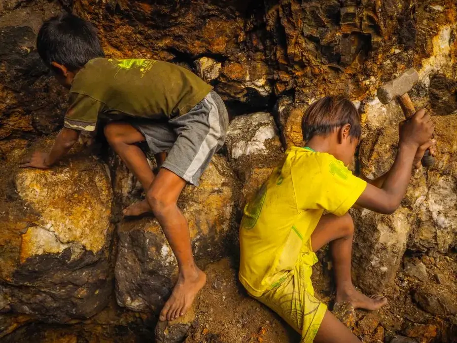 Yoyo, 10, and his friend, Duku, 8, hammer on rocks to break them up while working in a 20-foot-deep hole. Image by Larry C. Price. Indonesia, 2013. LARRY PRICE