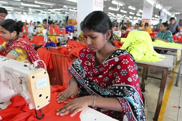 Mukhta Mollah, 19, is one of the 350 factory workers at Beauty Garments Pvt. Ltd. She earns $20 a week working eight hours or longer a day, six days a week. Although her salary may not amount to a lot, working in the factory has given her a measure of independence. Image by Kenneth R. Weiss. Bangladesh, 2014. Media file: la-la-fg-bangladesh-garment-worker02-jpg-20140312.png