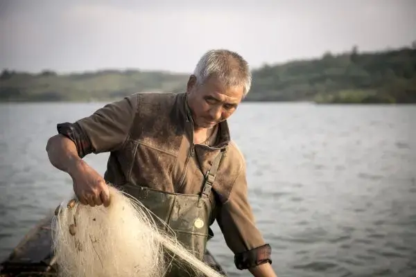 During the course of the year that Sharron Lovell filmed him, fisherman Cao Suizhou’s hair turned from jet black to white, a sign of stress for a man who otherwise endures his worries in silence. When asked what he wants people to know about China’s radical remedy to its water crisis, he said, “Just to understand what we’ve gone though, we know we can’t fight it or change anything, but people in Beijing should know where their water is coming from.” Image by Tom Wang. China, 2015. Media file: china_water_proj.jpg