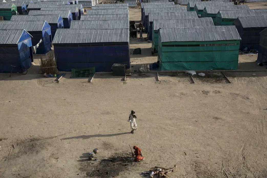 A young woman walks through Custom House, a large IDP camp on the outskirts of Maiduguri that is home to over 9,000 people. There are more than 1.7 million displaced in Northern Nigeria alone, and the number of shelters at refugee camps does not meet the needs of the huge population. The camps that do exist are often cut off from town and markets and frequent sites of suicide bombs. Image by Sarah A. Topol. Nigeria, 2017.