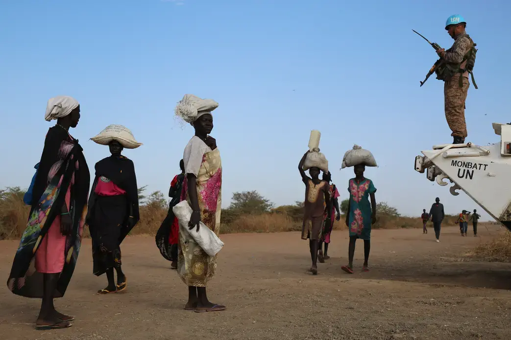 Internally displaced South Sudanese walk past a U.N. peacekeeper in Bentiu. Image by Cassandra Vinograd. South Sudan, 2016. Internally displaced South Sudanese walk past a U.N. peacekeeper in Bentiu. Image by Cassandra Vinograd. South Sudan, 2016.