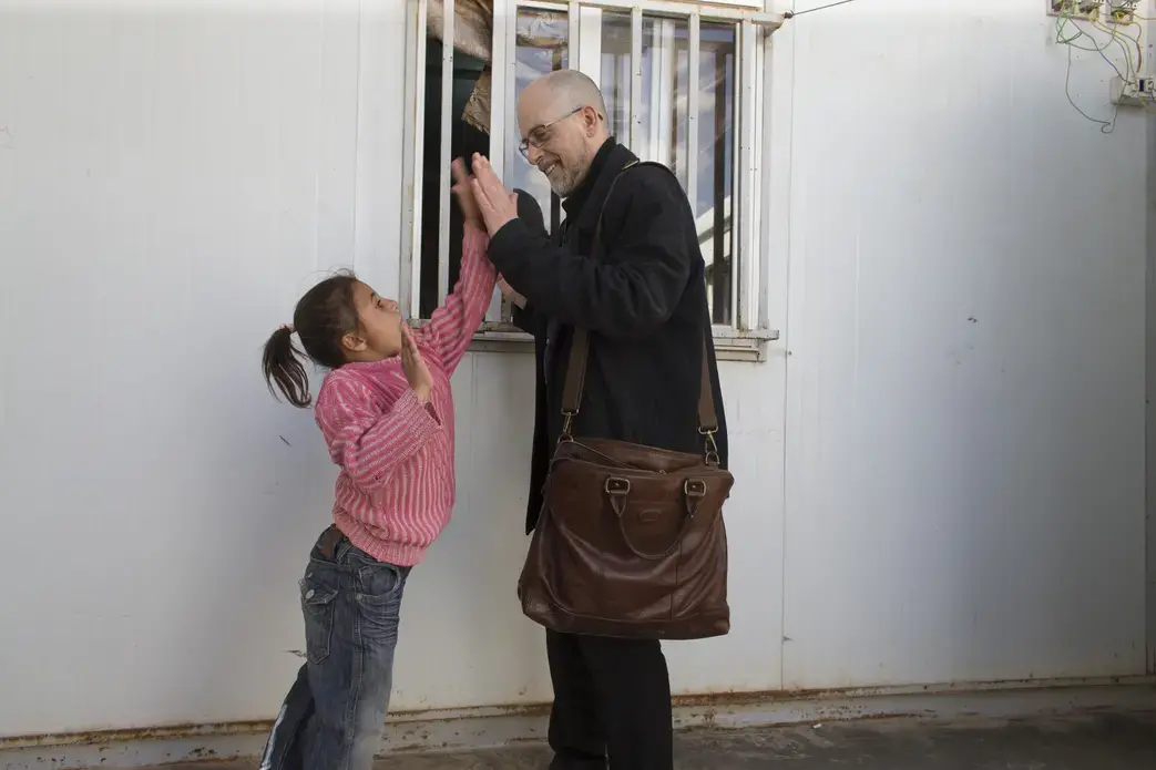 Reporter Mark Johnson plays with girls at a medical clinic at the Zaatari refugee camp in Jordan. Image by Mark Hoffman. Jordan, 2016. Media file: jordan_mark_johnson_1.jpg