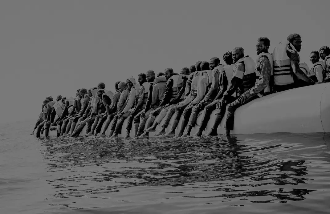 Roughly a hundred and fifty people wait to be rescued from an inflatable dinghy in the Mediterranean Sea, twenty miles north of Libya. The boat left with only enough fuel to reach international waters. Image by Ben Taub. Libya, 2016. Roughly a hundred and fifty people wait to be rescued from an inflatable dinghy in the Mediterranean Sea, twenty miles north of Libya. The boat left with only enough fuel to reach international waters. Image by Ben Taub. Libya, 2016.